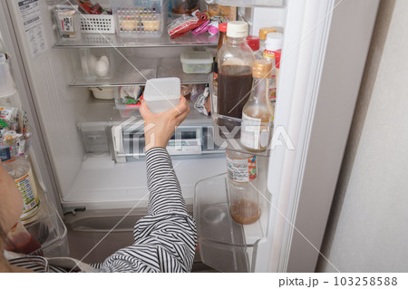 【冷蔵室からタッパを取り出す主婦】 103258588