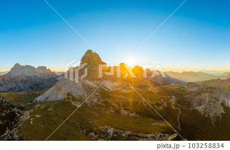 Endless rocky mountain ranges with hilly valleys in Alps at sunrise. Majestic landscape of Three Peaks of Lavaredo under clear sky aerial view 103258834