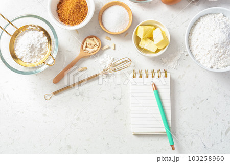 Notepad and pen with baking ingredients in bowls, flour, nuts, eggs, sugar and gold sieve and whisk on marble table, flatlay Notepad and pen with baking ingredients in bowls, flour, nuts, eggs, sugar and gold sieve and whisk on marble table, flatlay 103258960
