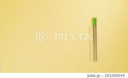 Metal straws for drinks and a brush for cleaning them on a yellow background Metal straws for drinks and a brush for cleaning them on a yellow background 103260044