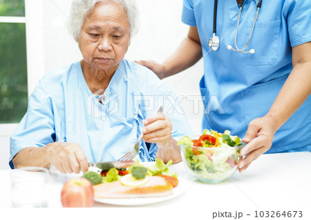 Asian elderly woman patient eating salmon stake and vegetable salad for healthy food in hospital. Asian elderly woman patient eating salmon stake and vegetable salad for healthy food in hospital. 103264673