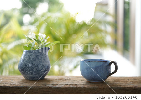 Blue coffee cup and white flower in a blue vase 103266140