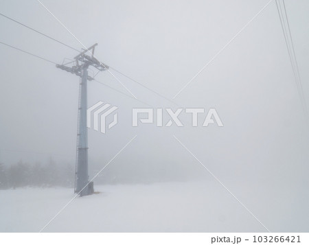 Ski lift in white thick fog. End of winter season with melting snow Ski lift in white thick fog. End of winter season with melting snow 103266421