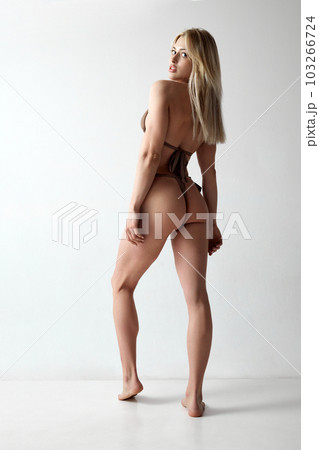 Full-length image of attractive young woman with fit body, back, buttocks posing in swimsuit against grey studio background Full-length image of attractive young woman with fit body, back, buttocks posing in swimsuit against grey studio background 103266724