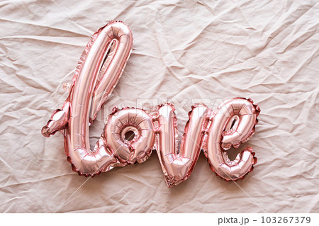 Word Love from foil pink balloons on textile background. Monochrome festive composition. Word Love from foil pink balloons on textile background. Monochrome festive composition. 103267379