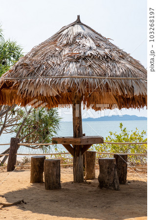 Seating under a wooden hut shelter, located by the sea. 103268197