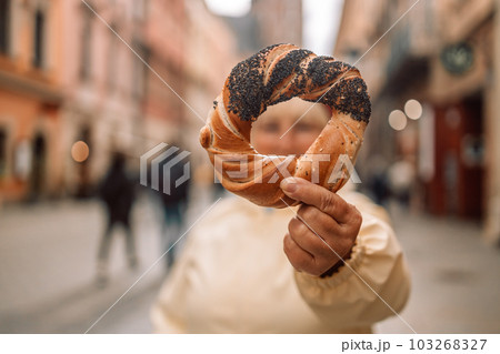 Senior woman holding prezel, traditional polish snack on the Market square in Krakow 103268327