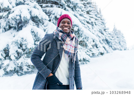 african american handsom man in red hat and stylish plaid coat look at camera with toothy snow- white smile outdoor in park african american handsom man in red hat and stylish plaid coat look at camera with toothy snow- white smile outdoor in park 103268948