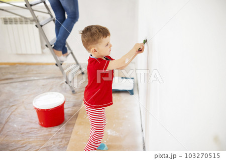 Mother and child son paint the wall with paint using roller and brush 103270515