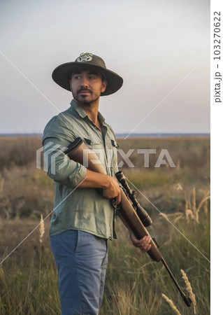 ranger in a hat stands in a field with a gun 103270622