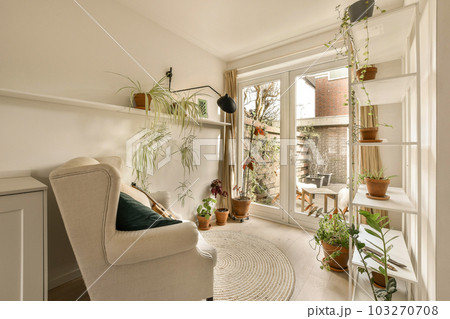 a living room with plants on the wall, and a chair in the corner by the door to the patio a living room with plants on the wall, and a chair in the corner by the door to the patio 103270708