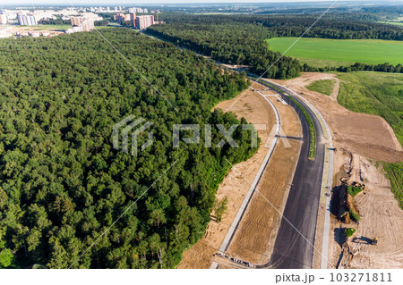 Aerial view of the road under construction leading to the city through the forest 103271811