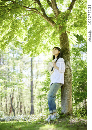 森の中でリラックスしながら森林浴を楽しむ30代日本人女性の初夏のイメージ 103277131