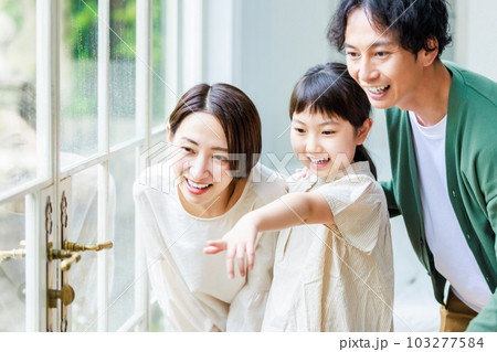 リビングの窓から外を見る親子 103277584