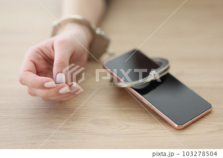 Hand of woman attached to smartphone with handcuffs 103278504