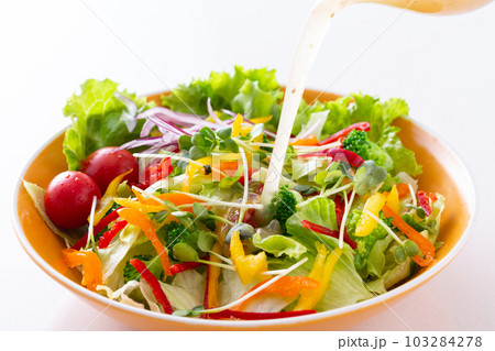 野菜サラダにイタリアンドレッシングをかける 103284278