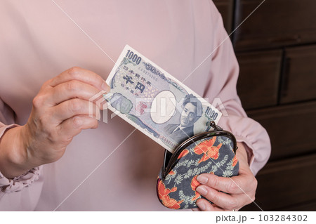 【がま口から1000円札を出す主婦】 103284302