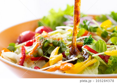 野菜サラダに和風ドレッシングをかける 103284378