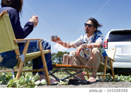 屋外に椅子とテーブルを設置して、くつろぐミドルシニアのカップル 103288308