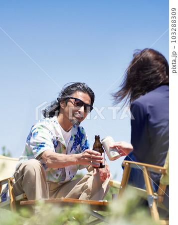 青空のもと座って乾杯するミドルシニアのカップル 103288309