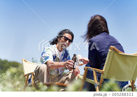 青空のもと座って乾杯するミドルシニアのカップル 103288311