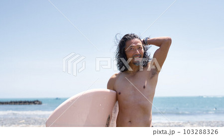 サーフボードを抱える長髪のミドル男性サーファー 103288326