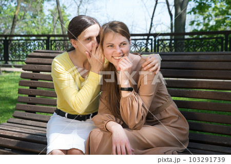 Two girls gossip in the park 103291739