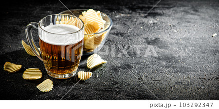 Glass of beer with potato chips. Glass of beer with potato chips. 103292347