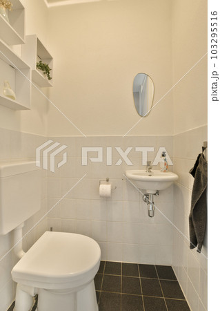 a small bathroom with black and white tiles on the floor, sink, toilet, mirror and towel hanging on the wall 103295516