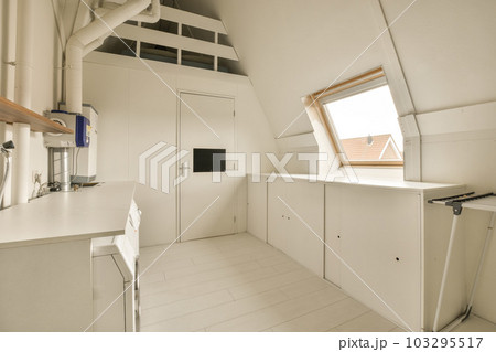 a kitchen area in an attic style house with white walls and wood trim on the ceiling, windows, and skylights 103295517