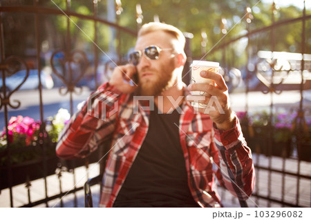 Handsome young man holding mobile phone and drinking coffee while sitting in the rest area. 103296082