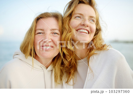 Redhead senior mother and her beautiful adult daughter are walking together and laughing 103297360