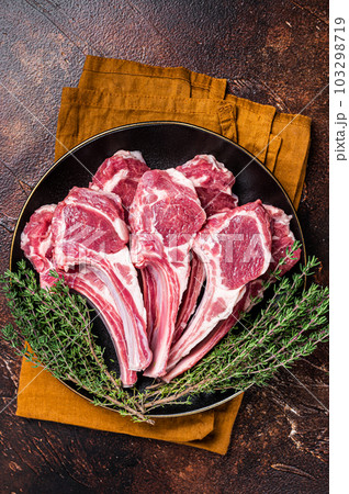 Raw lamb chops, fresh mutton meat cutlets on a ribs. Dark background. Top view 103298719