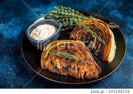 Fried cabbage steaks with sauce on a black plate. Blue background. Top view 103298728