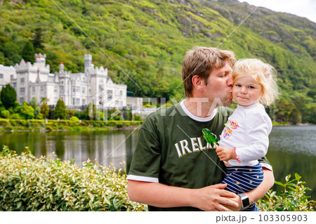 father with little daughter with Kylemore Abbey on background. Man and toddler girl. Family and small children vacations in Ireland 103305903
