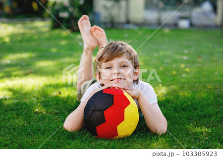 Happy active kid boy playing soccer with ball in German flag colors. Healthy child having fun with football game and action outdoors Happy active kid boy playing soccer with ball in German flag colors. Healthy child having fun with football game and action outdoors 103305923