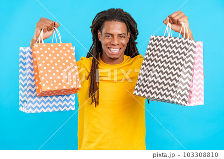 Happy Latin man with dreadlocks raising many shopping bags 103308810