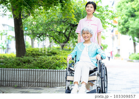 車椅子のシニア女性と若い介護士 車椅子のシニア女性と若い介護士 103309857