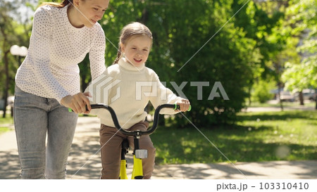 child learn ride bike. mother daughter girl park. happiness smile little child mom. dream family., candid lifestyle footage, mom little daughter learn ride bike nature, caring mother who teaches child learn ride bike. mother daughter girl park. happiness smile little child mom. dream family., candid lifestyle footage, mom little daughter learn ride bike nature, caring mother who teaches 103310410