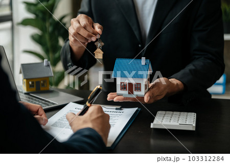 Real estate broker agent presenting and consult to customer to decision making sign insurance form agreement, home model, concerning mortgage loan offer Real estate broker agent presenting and consult to customer to decision making sign insurance form agreement, home model, concerning mortgage loan offer 103312284