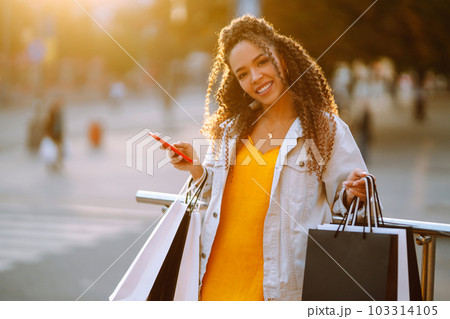 Young woman with shopping bags walking on street. Sale, shopping and happy people concept. Young woman with shopping bags walking on street. Sale, shopping and happy people concept. 103314105