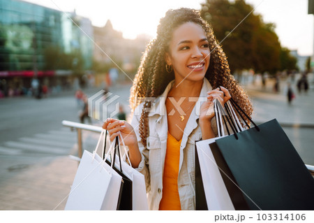 Young woman with shopping bags walking on street. Sale, shopping and happy people concept. Young woman with shopping bags walking on street. Sale, shopping and happy people concept. 103314106