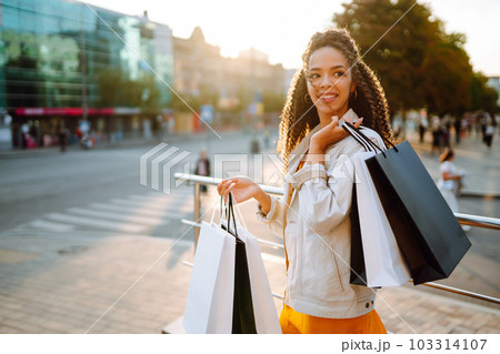 Young woman with shopping bags walking on street. Sale, shopping and happy people concept. 103314107