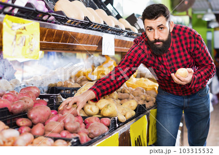 Young male seller offering potatoes Young male seller offering potatoes 103315532