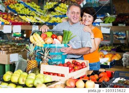 Couple standing with basket of purchases 103315622