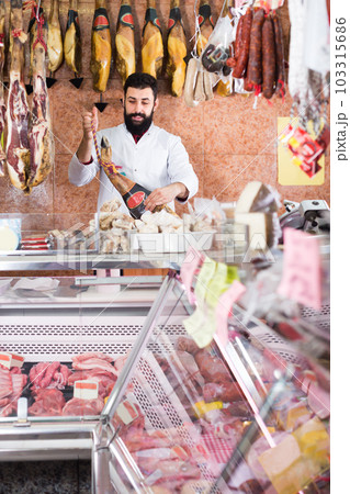 Young male seller showing jamon Young male seller showing jamon 103315686