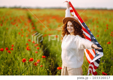 Young woman hold waving american USA flag in in the poppy field. Independence Day, 4th July. Young woman hold waving american USA flag in in the poppy field. Independence Day, 4th July. 103316017