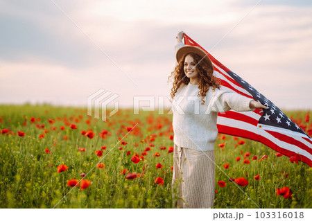 Young woman hold waving american USA flag in in the poppy field. Independence Day, 4th July. Young woman hold waving american USA flag in in the poppy field. Independence Day, 4th July. 103316018