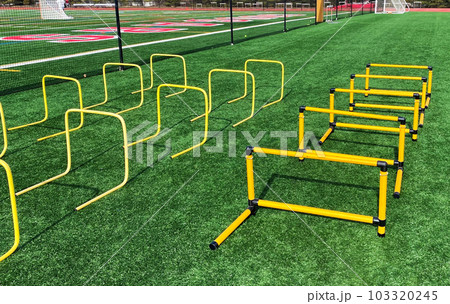 Plastic yellow hurdles set up on a turf field Plastic yellow hurdles set up on a turf field 103320245