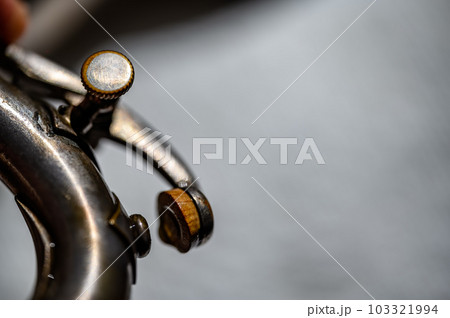 Selective focus on a water key of an aged wind instrument trumpet.  103321994